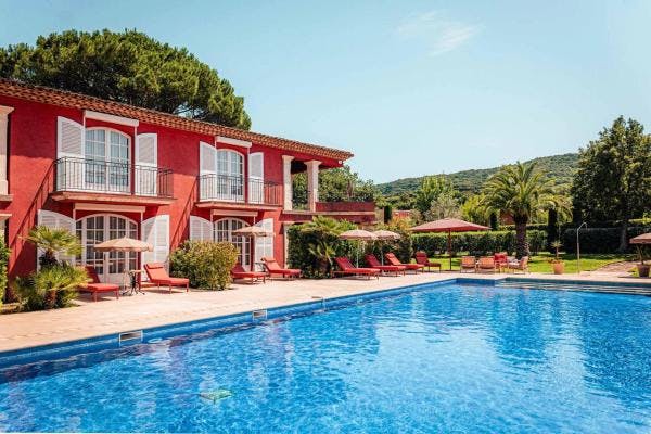 Swimming pool and red building of Domaine de l'Astragale hotel in Saint Tropez.