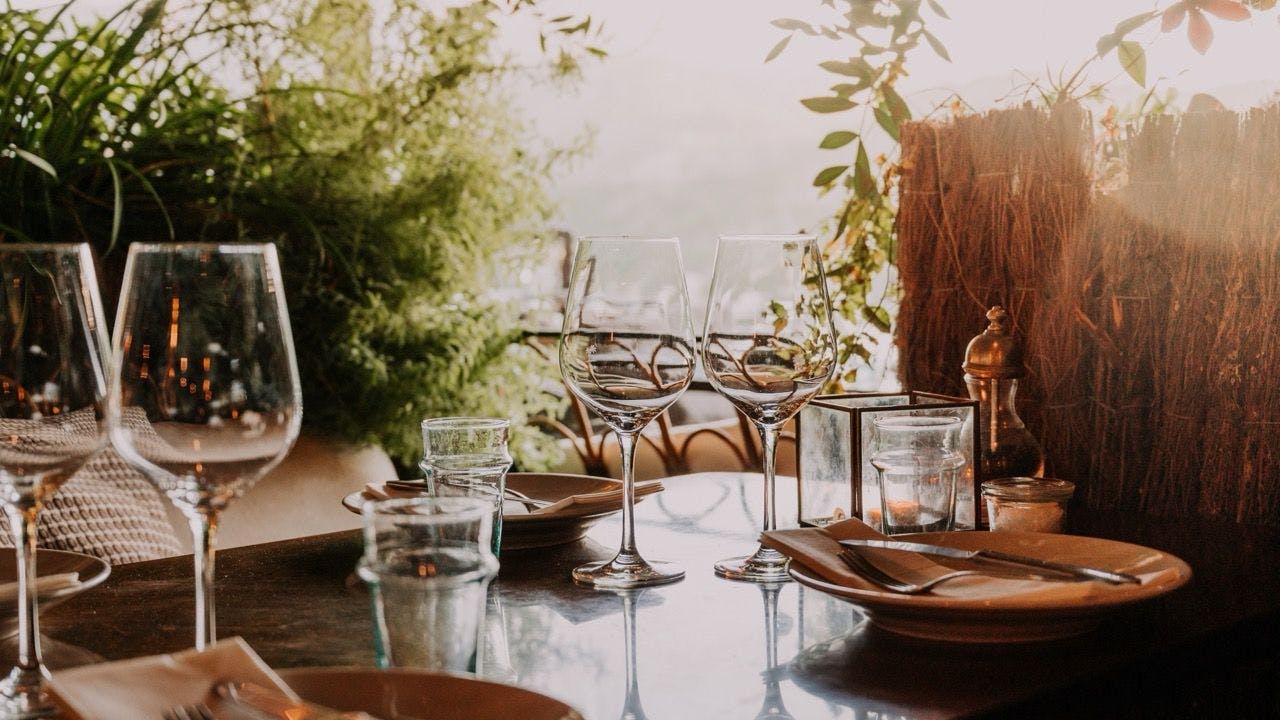 Decorated outdoor dinner table with plants and tableware