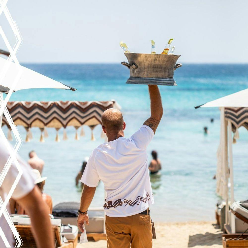 Waiter carrying a cooler full of champagne in Mykonos beach club Kalua