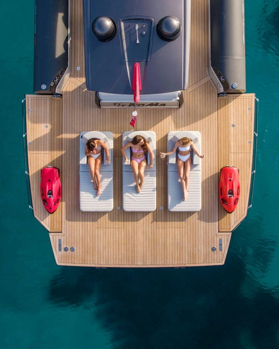 Three women sunbathing on the sundeck of a yacht.