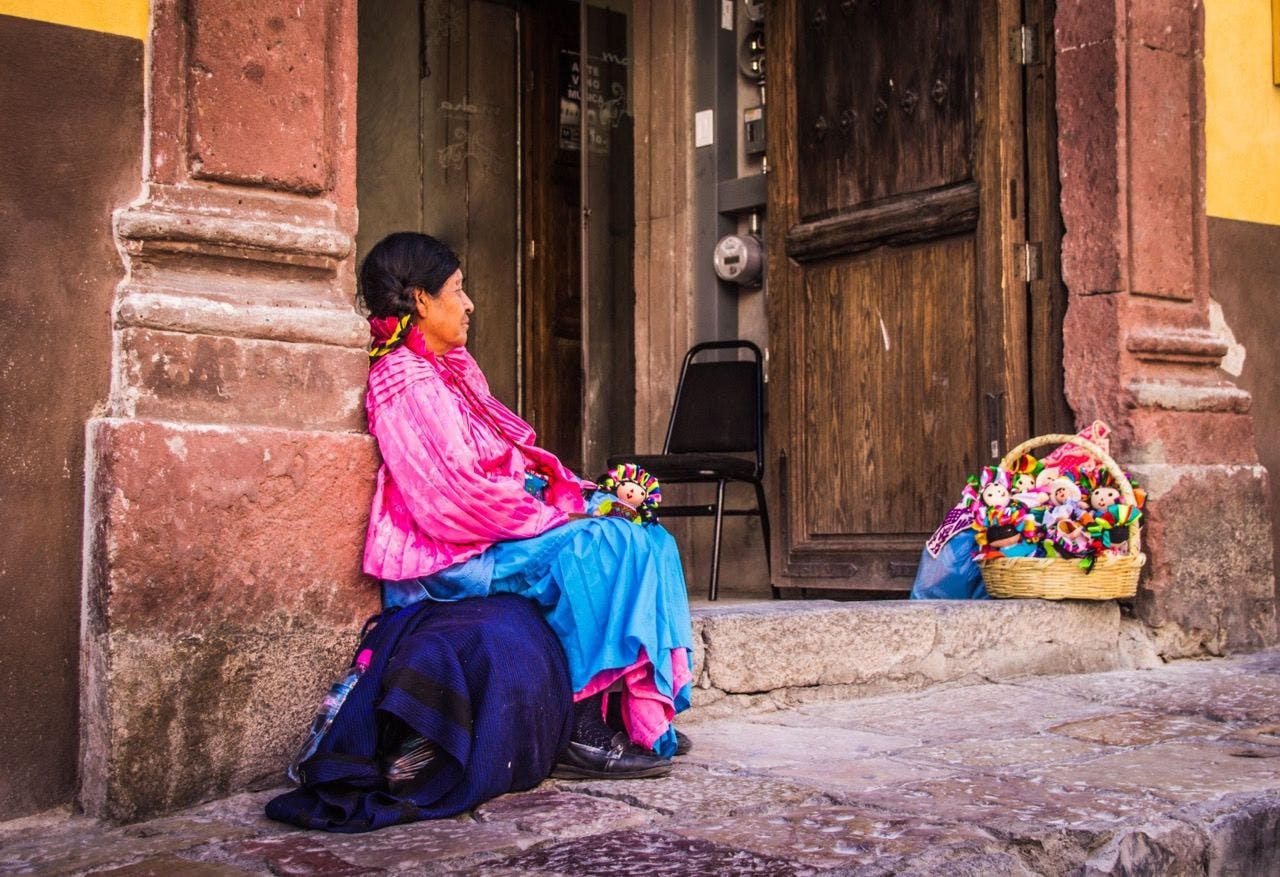 Local woman sitting in traditional clothing on the street in Mexico