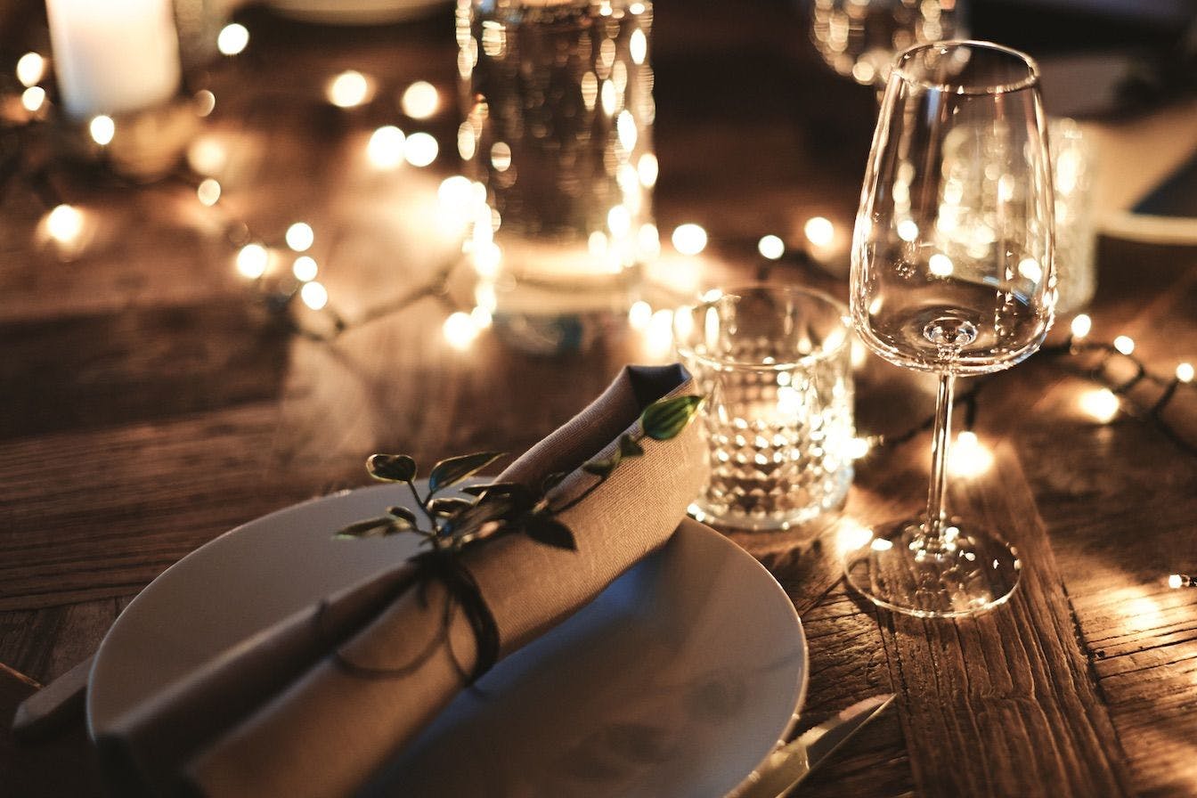 Decorated dinner table with tableware and string lights