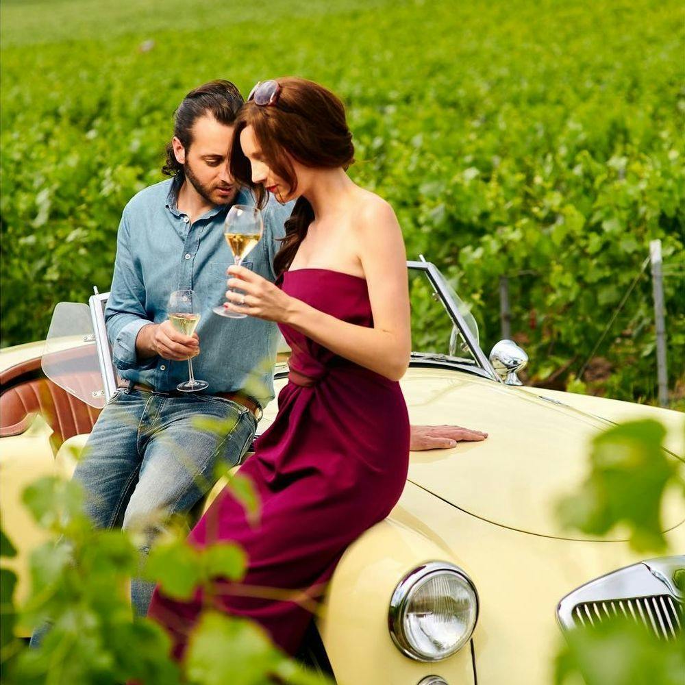 Couple sitting on a vintage car and drinking champagne.