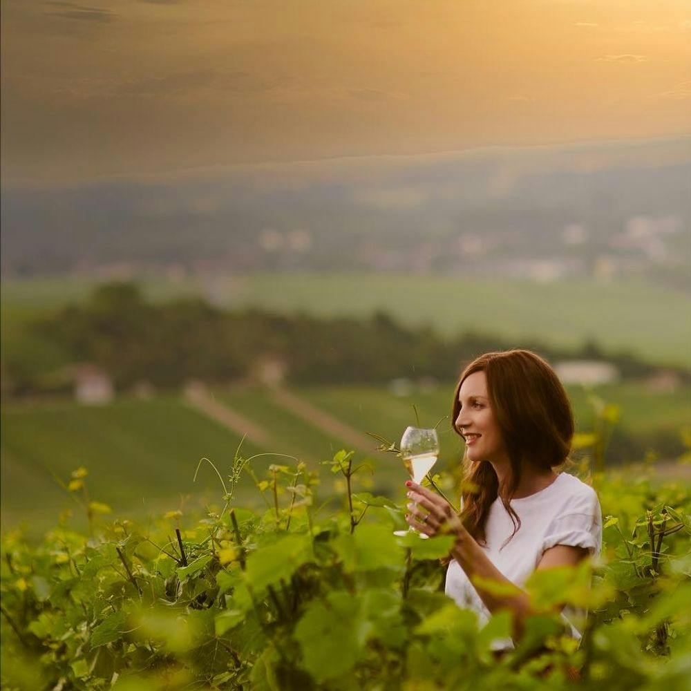 Lady with a glass of Taittinger champagne standing in a vineyard.