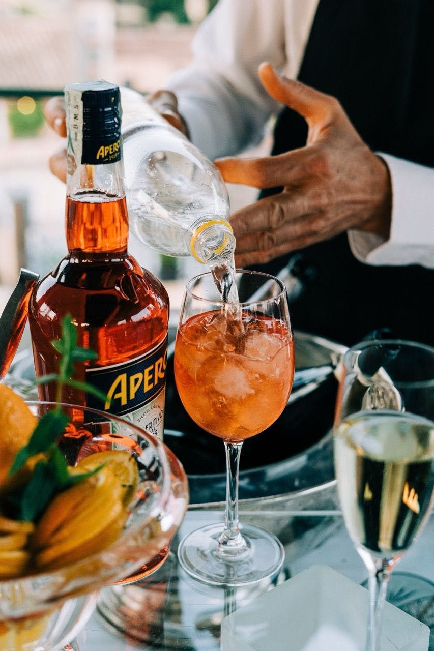 Aperol bottle and waiter making a cocktail