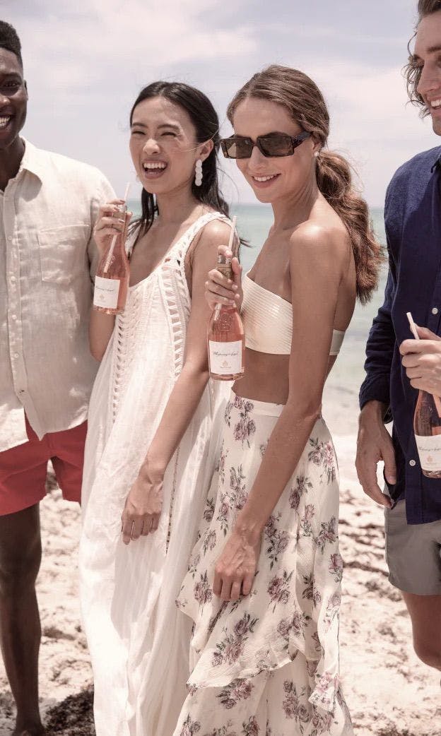 Beautiful women standing in a beach party with French rose wine