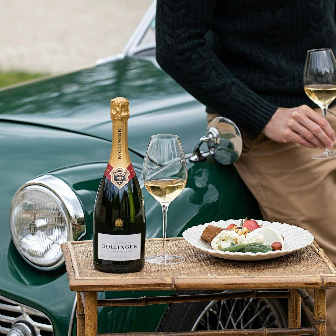 Man with a vintage car and a bottle of Bollinger champagne.