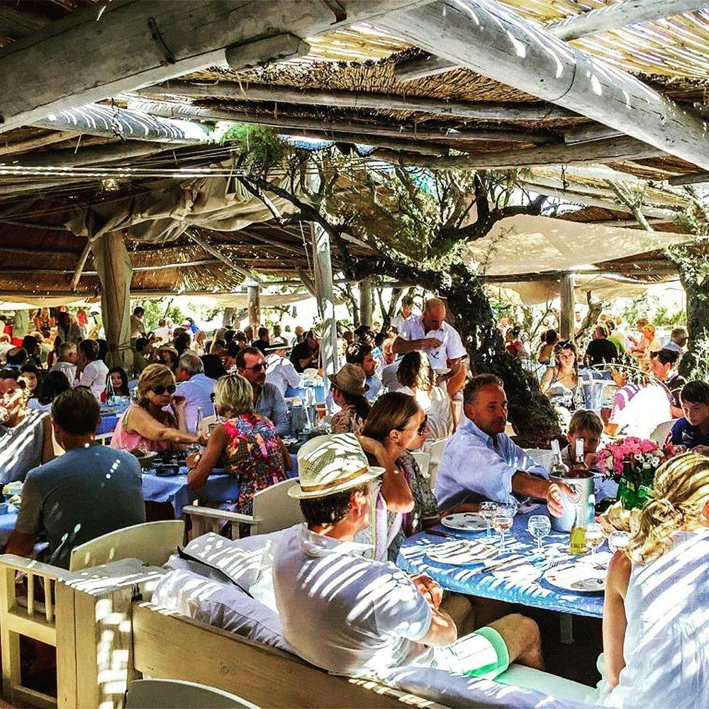 People sitting behind tables in Saint-Tropez beach club Le Club 55