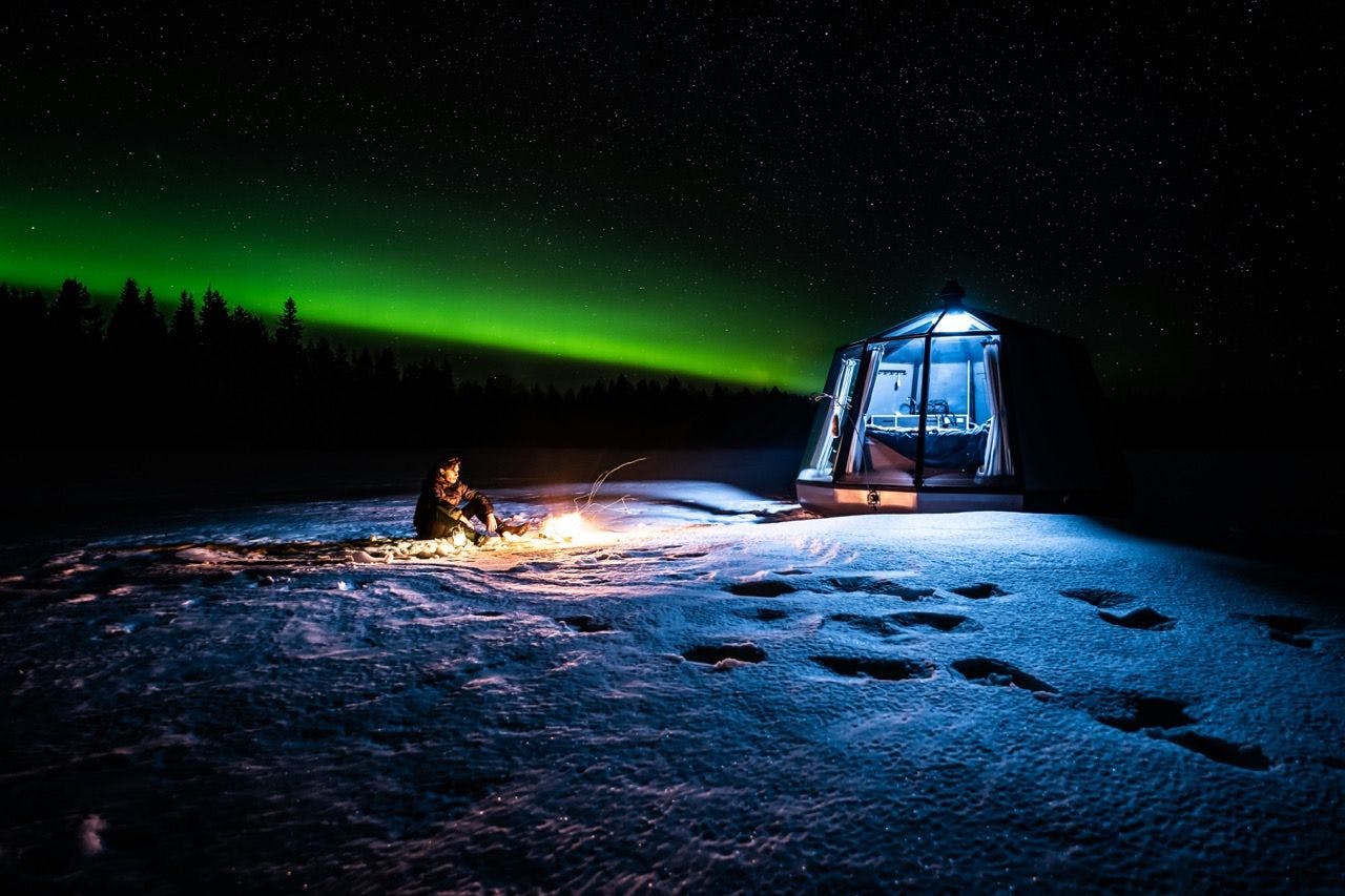 Man sitting in front of the glass igloo in Lapland.