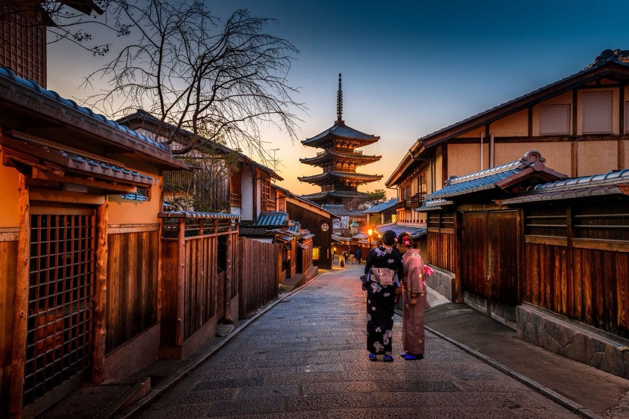 Two geishas walking on a street in Japan.