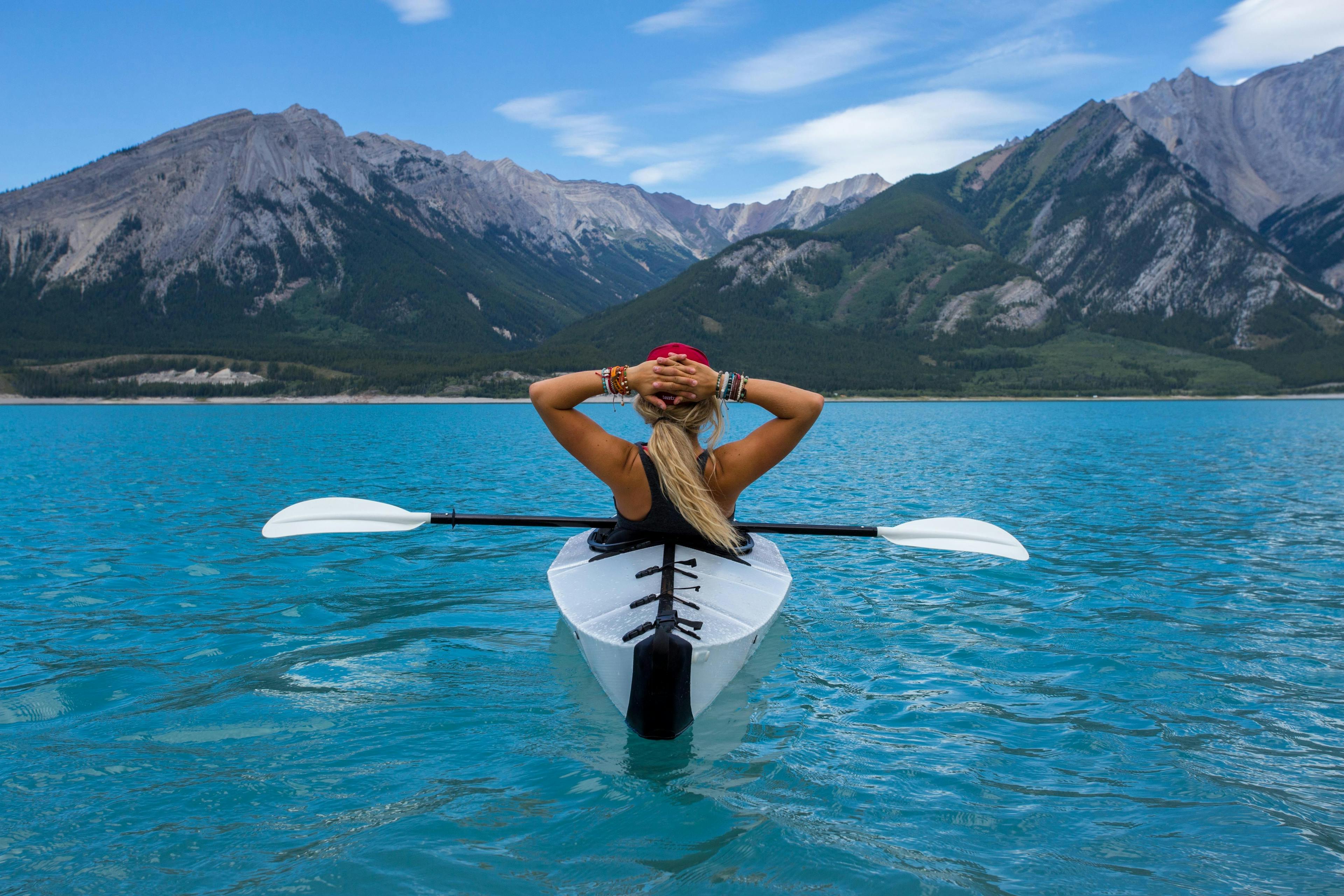 Woman kayaking on a lake next to mountains