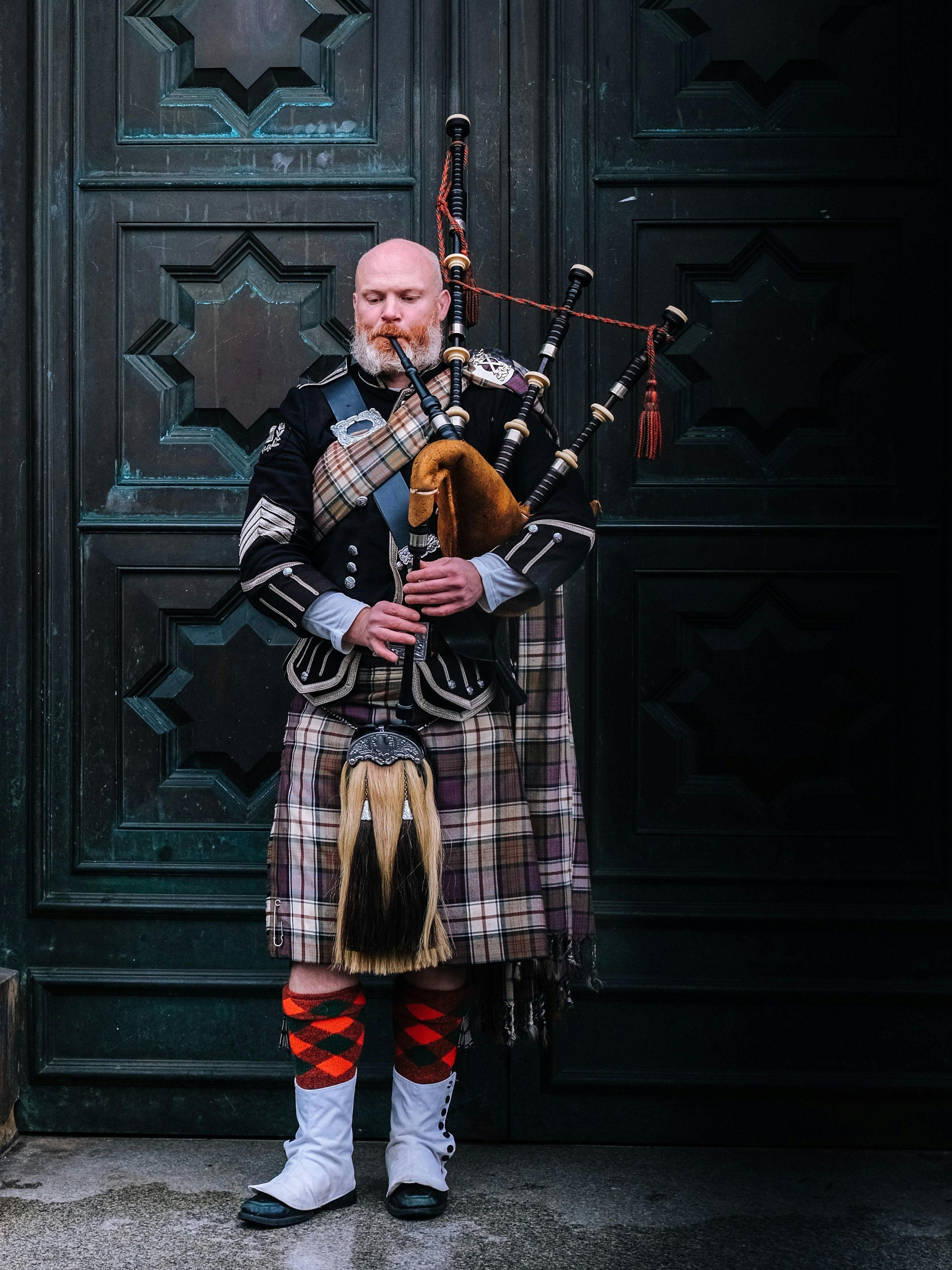 Man wearing kilt playing bagpipe in Scotland.