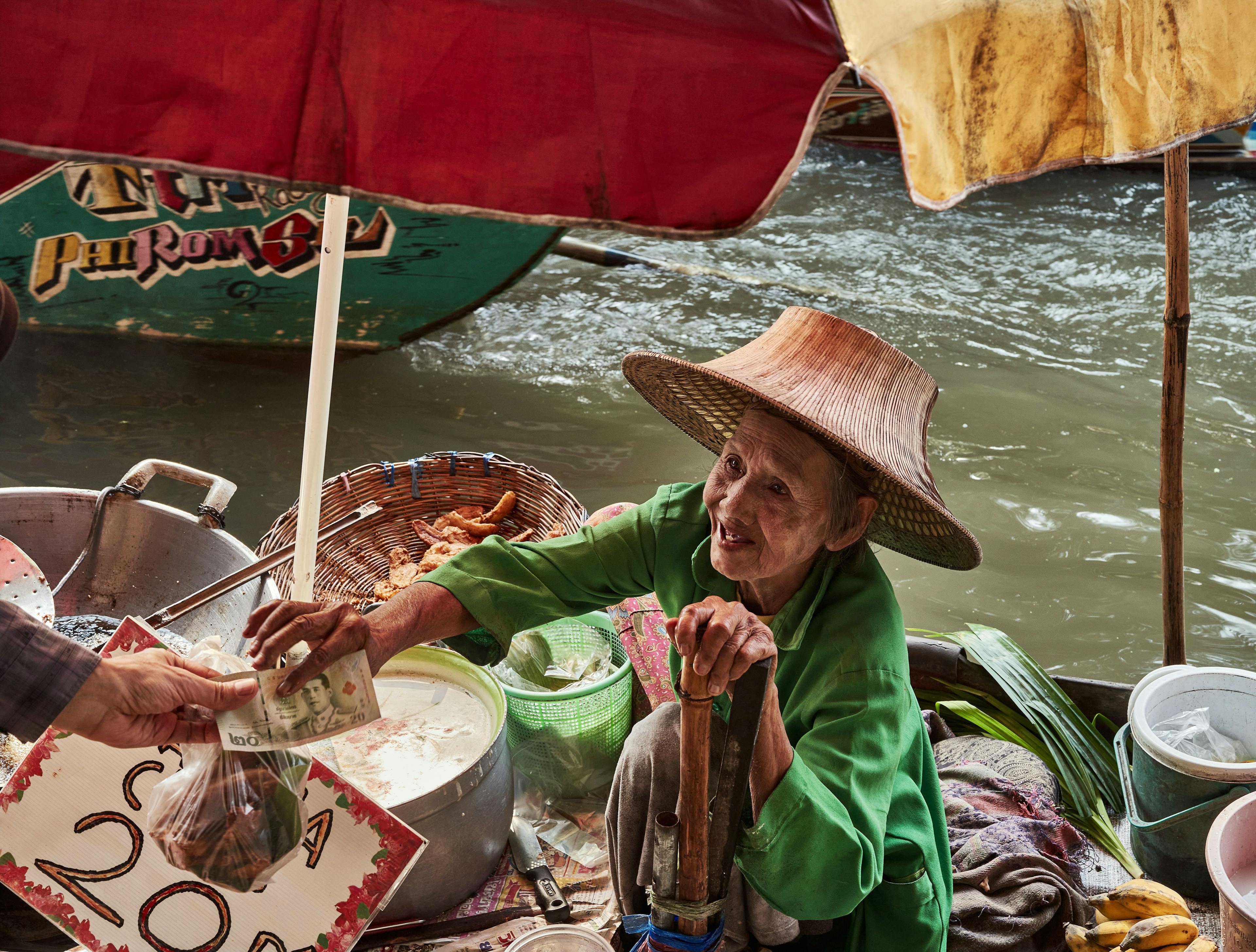 Old Thai woman selling snacks in floating market near Bangkok Thailand.