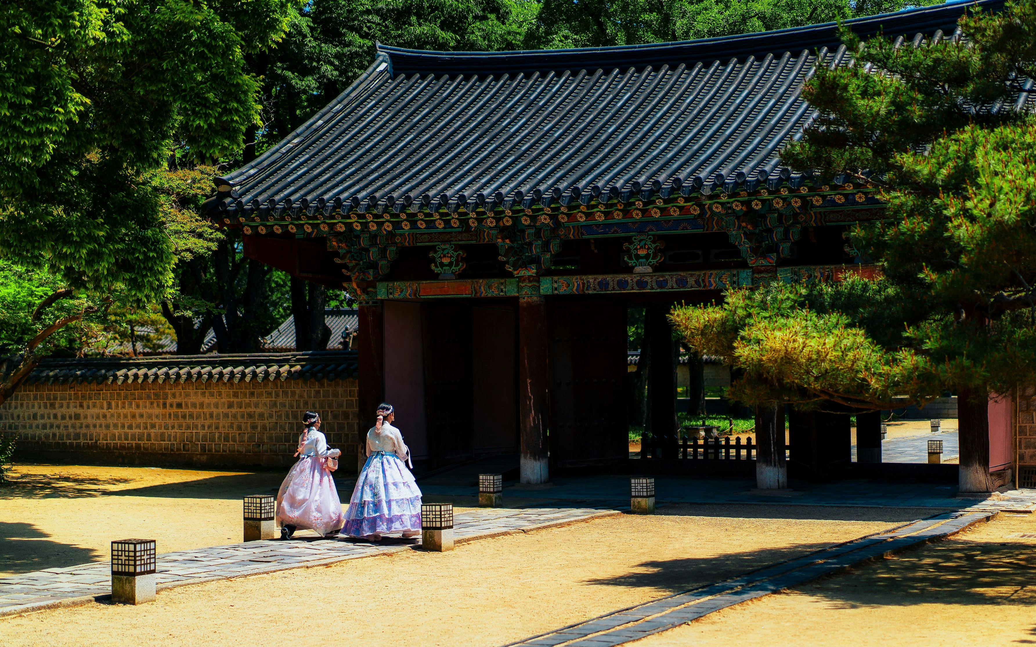 Women in traditional costumes walking into temple in South Korea.