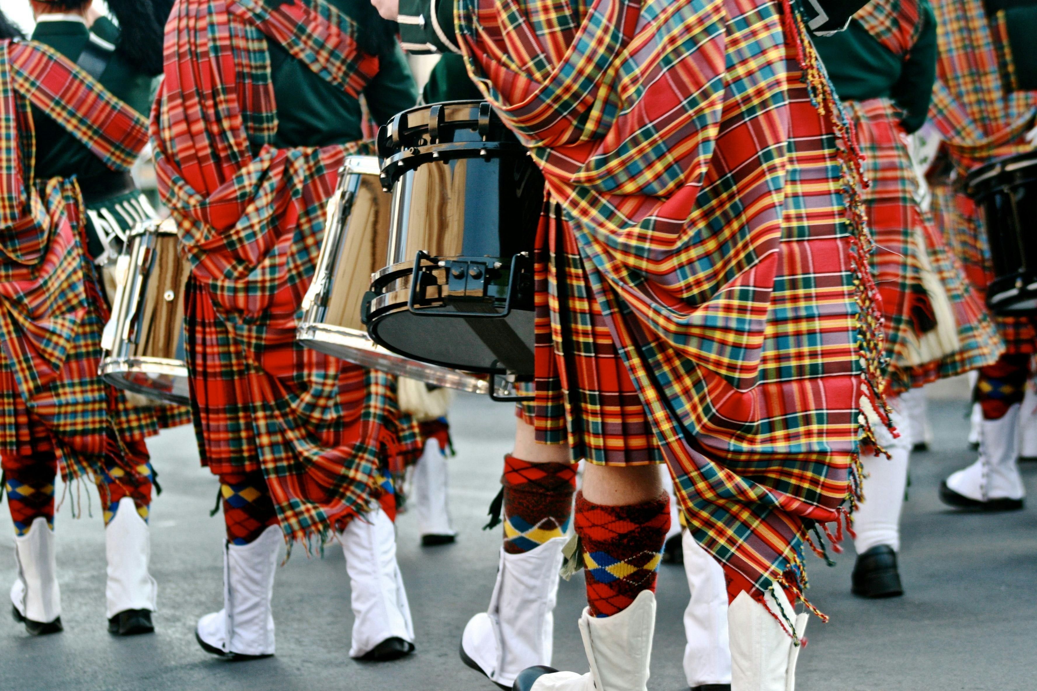 People wearing Scottish kilts and playing music.