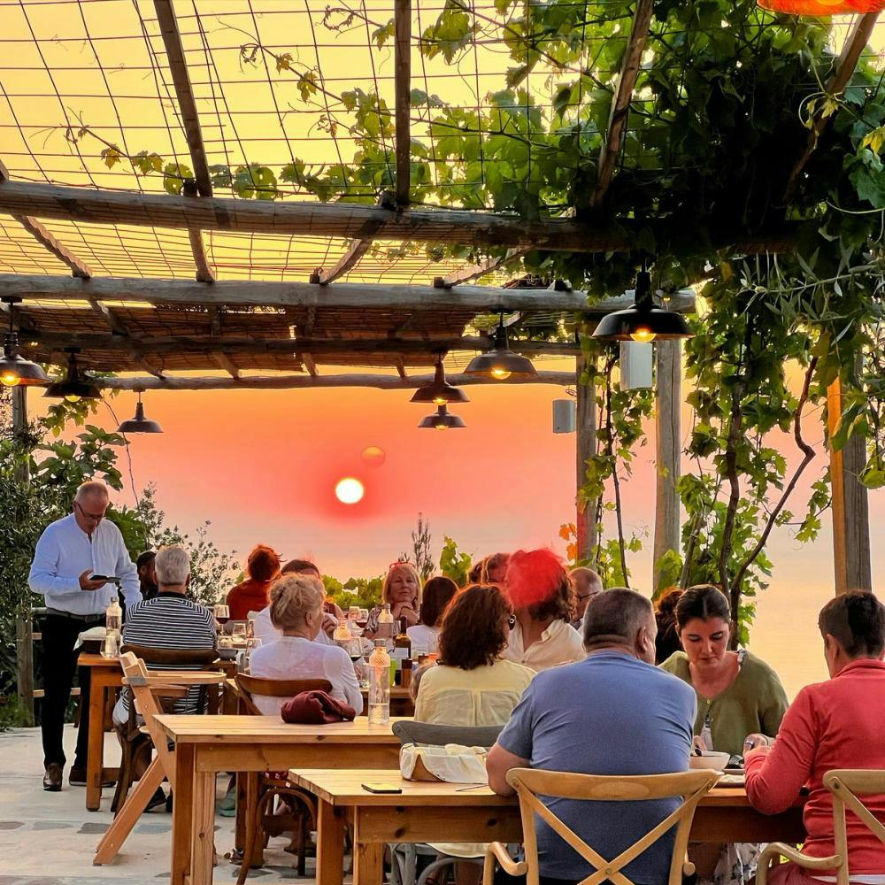 People sitting and enjoying sunset in home restaurant in Ikaria Greece